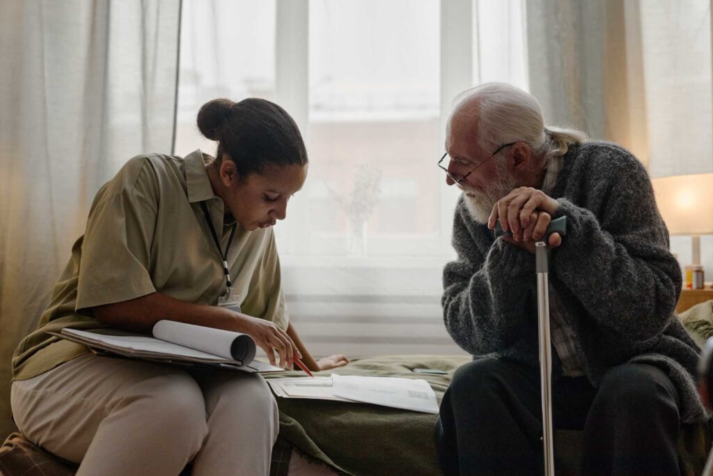Young Adult Black Woman Social Worker Assisting Senior Caucasian Man